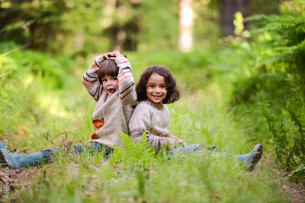 Two boys in identical sweaters sitting on a forest road Two boys in identical sweaters sitting on a forest road