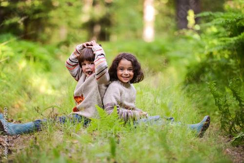 Two boys in identical sweaters sitting on a forest road