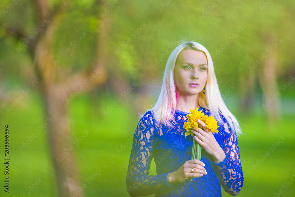 Beauty Concepts. Sensual Caucasian Blond Girl with Bunch of Daffodils Dreaming. Against Blurred Nature Background. Beauty Concepts. Sensual Caucasian Blond Girl with Bunch of Daffodils Dreaming. Against Blurred Nature Background.