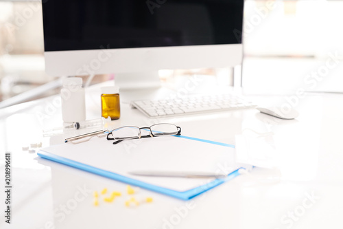 Close up of doctors tools lying on white desk with computer in modern office  copy space