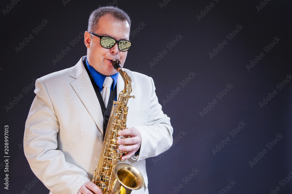 Fototapeta premium Music Concepts. Portrait of Caucasian Mature Male Saxophone Player Posing In Sunglasses With Musical Notes Reflections With Sax. Against Black Background.