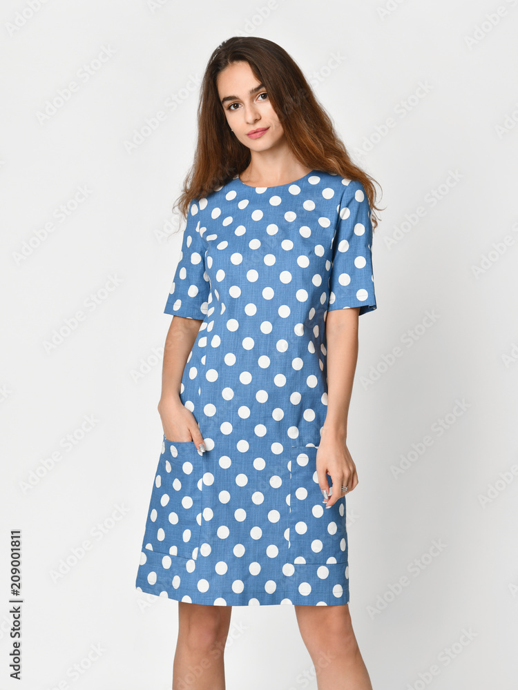 Young beautiful woman posing in new blue stripes casual summer dress on grey Young beautiful woman posing in new blue stripes casual summer dress on grey