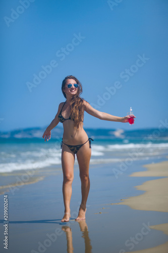 young girl in bikini walks on a tropical beach