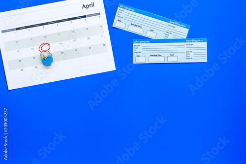 Plan a trip. Buy airplane tickets. Tickets near calendar with date circled on blue background top view copy space © 9dreamstudio