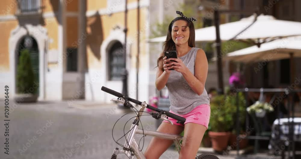 Cute smiling Latina woman on her bicycle using smartphone for directions, Carefree young woman having fun on summer day, 4k Cute smiling Latina woman on her bicycle using smartphone for directions, Carefree young woman having fun on summer day, 4k