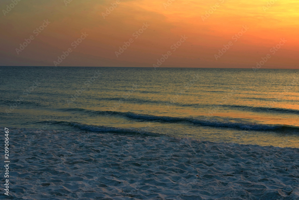 Beach and sand show waves in the sea on orange or golden sky background