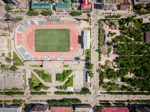 Aerial photography of a modern  stadium with green field for football, a big road, city traffic and parks on a warm summer day. Helicopter drone shot