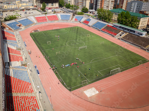 Aerial photography of a modern  stadium with green field for football, a big road, city traffic and parks on a warm summer day. Helicopter drone shot