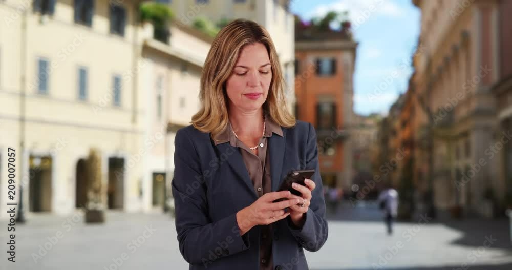 Rome businesswoman texting with cellphone, Smiling portrait of Caucasian woman in a business suit using mobile phone outside, 4k Rome businesswoman texting with cellphone, Smiling portrait of Caucasian woman in a business suit using mobile phone outside, 4k