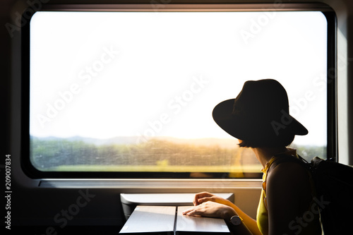 A beautiful hipster asian woman traveling on the train looking to the view through the window.