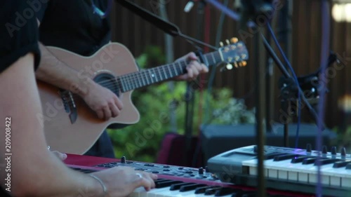 Music band playing on keyboards and guitar outdoors event wedding active sound back side close up view. Two unrecognizable musicians perform electronic instruments slow motion live concert inspiration photo