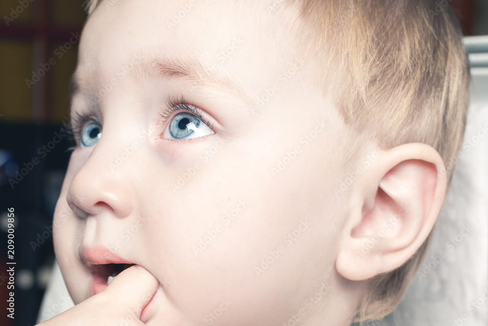 Beautiful child bites his fingers in his mouth Beautiful child bites his fingers in his mouth
