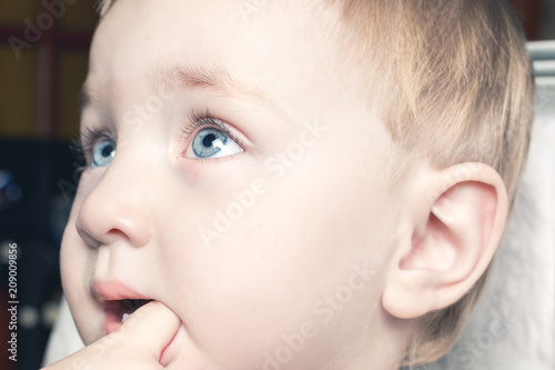 Beautiful child bites his fingers in his mouth
