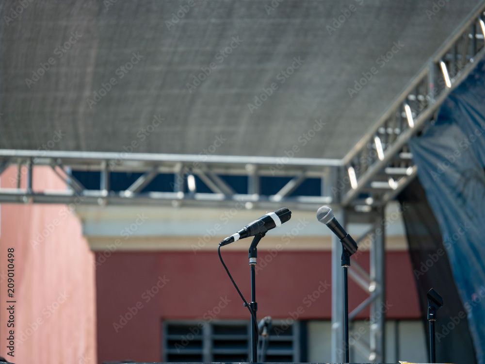 Two digital microphones on stage facing each other under a canopy