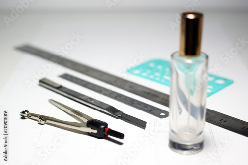 Equipment for workshop packaging design and development with glass bottle for cosmetics or product. Selective focus on cutter knife.