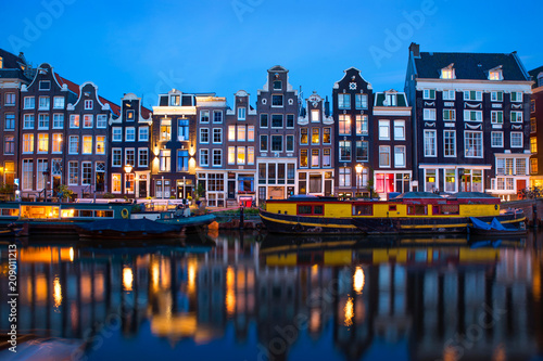 Amsterdam canal  with typical dutch houses and houseboats at evening with beautiful water reflections, Holland, Netherlands. 
