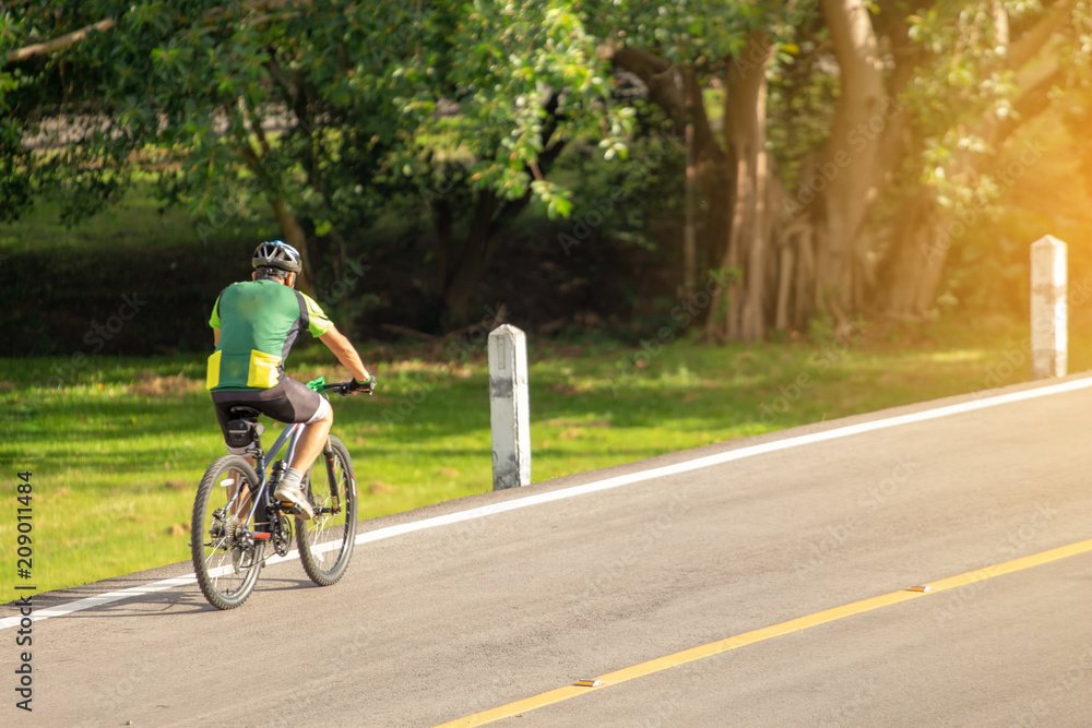 Cyclist in the park with orange sunlight scattered throughout