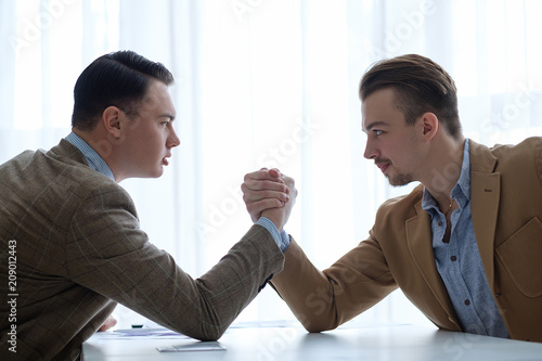 business men face off and opposition.  arm wrestling to determine leadership. professional competition photo