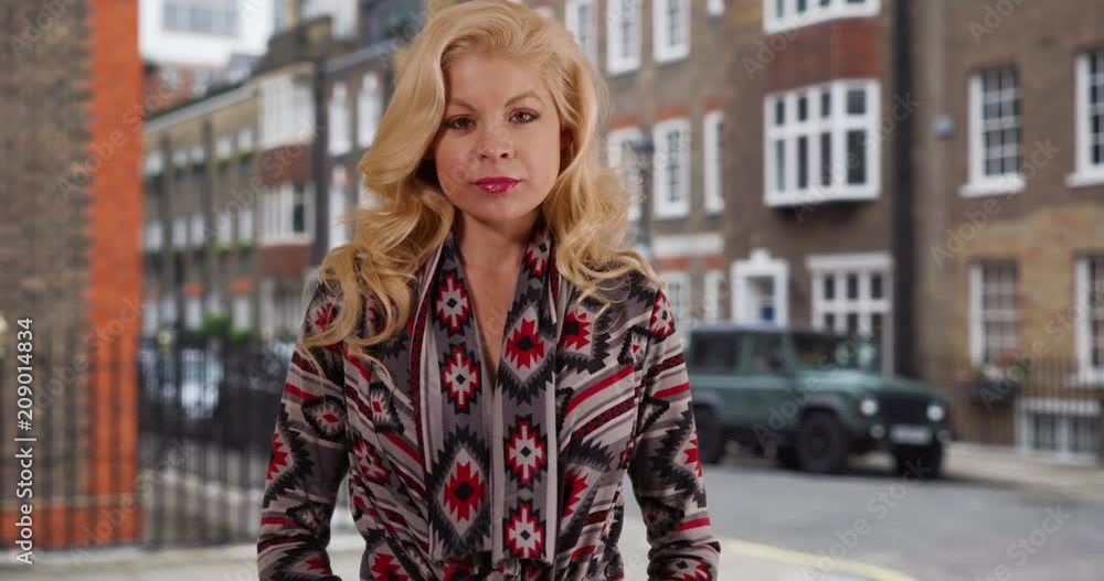 Pretty, blonde Caucasian woman smiling at camera on a London street, Cheerful smiling young woman stands outside apartment building, posing for portrait, 4k Pretty, blonde Caucasian woman smiling at camera on a London street, Cheerful smiling young woman stands outside apartment building, posing for portrait, 4k