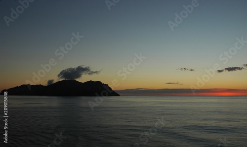 A smoking volcanic island at sunset.