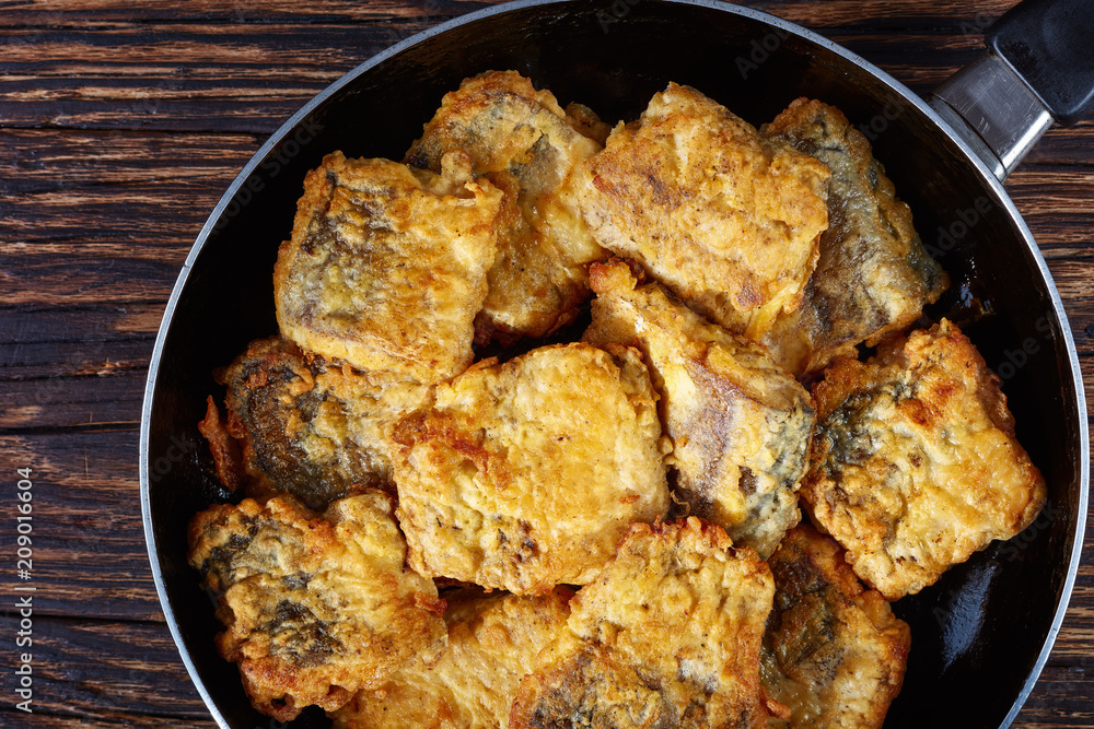 fried pieces of hake on a skillet fried pieces of hake on a skillet