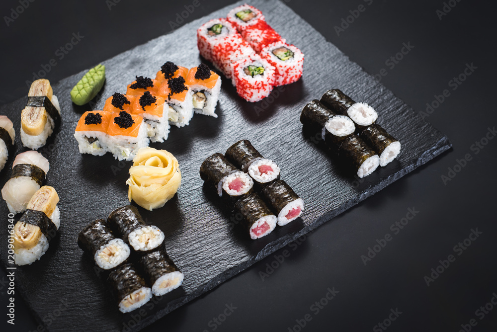 A set of different sushi rolls with caviar on black background A set of different sushi rolls with caviar on black background