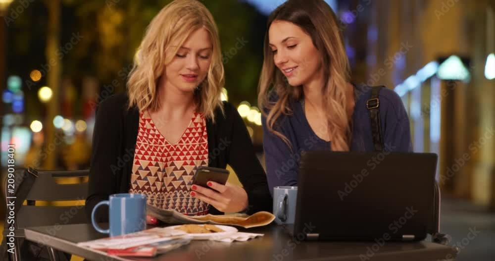 Pretty blonde woman using smartphone with friend to navigate destination in Champs Elysees in Paris, France, Lovely traveling women sitting and using smart phone in French shopping district, 4k Pretty blonde woman using smartphone with friend to navigate destination in Champs Elysees in Paris, France, Lovely traveling women sitting and using smart phone in French shopping district, 4k