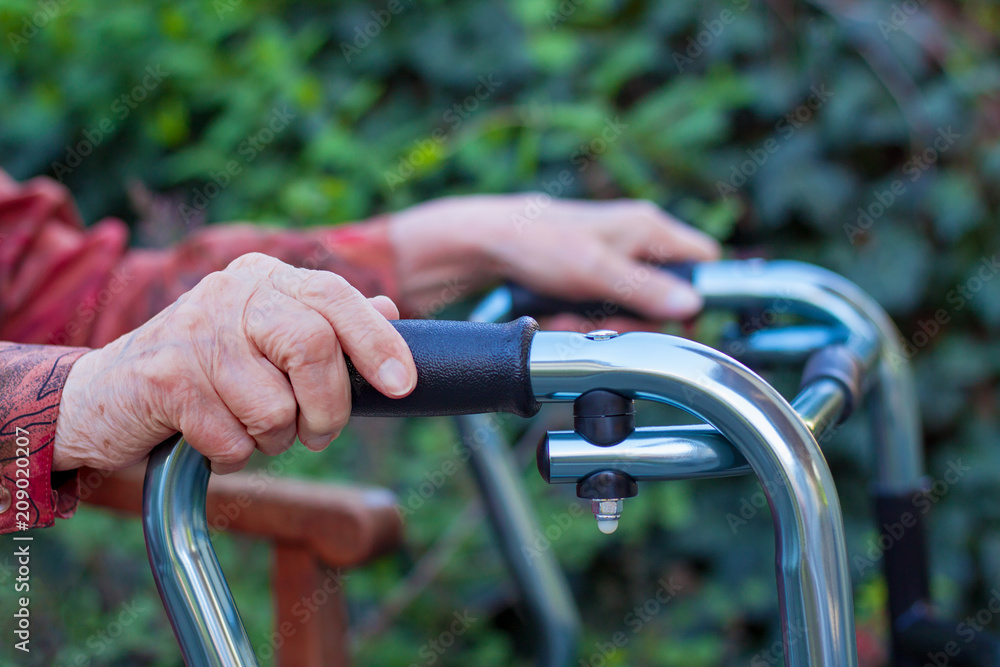Elderly woman handing with two hands a walker