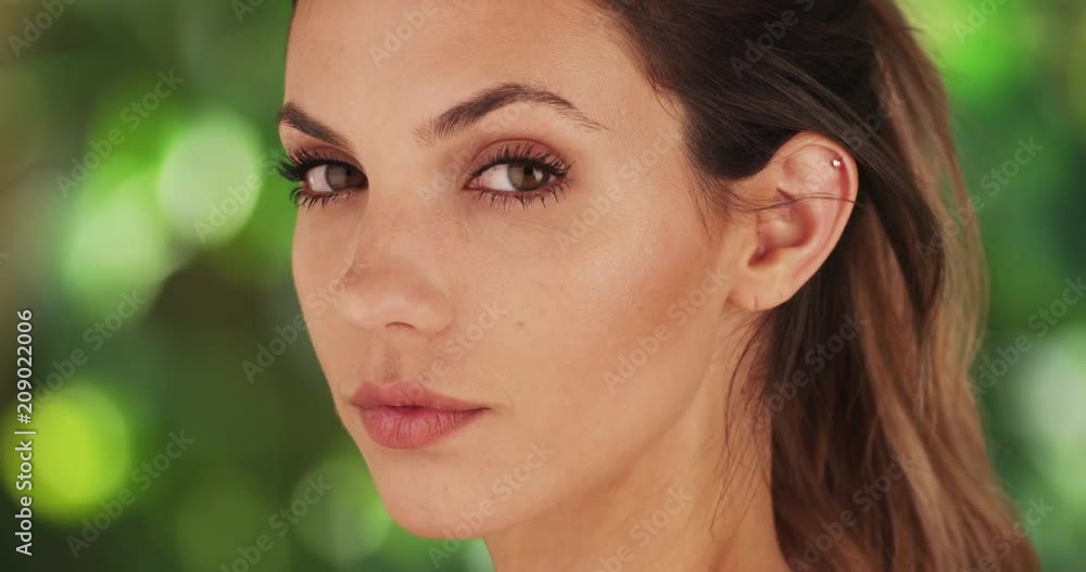Close-up profile of beautiful model turning head towards camera in front of bright green background, Headshot of attractive young woman posing for camera on green and white background, 4k Close-up profile of beautiful model turning head towards camera in front of bright green background, Headshot of attractive young woman posing for camera on green and white background, 4k