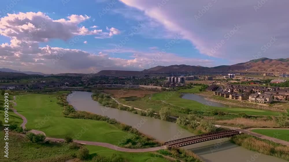 Aerial view of a golf course, river, bridge and golf carts as people enjoy golfing Aerial view of a golf course, river, bridge and golf carts as people enjoy golfing