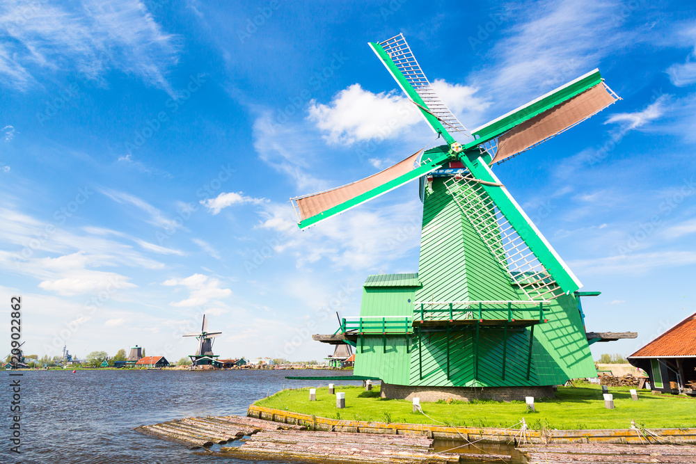 Dutch typical landscape. Traditional old dutch windmill against blue cloudy sky in the Zaanse Schans village, Netherlands. Famous tourism place.