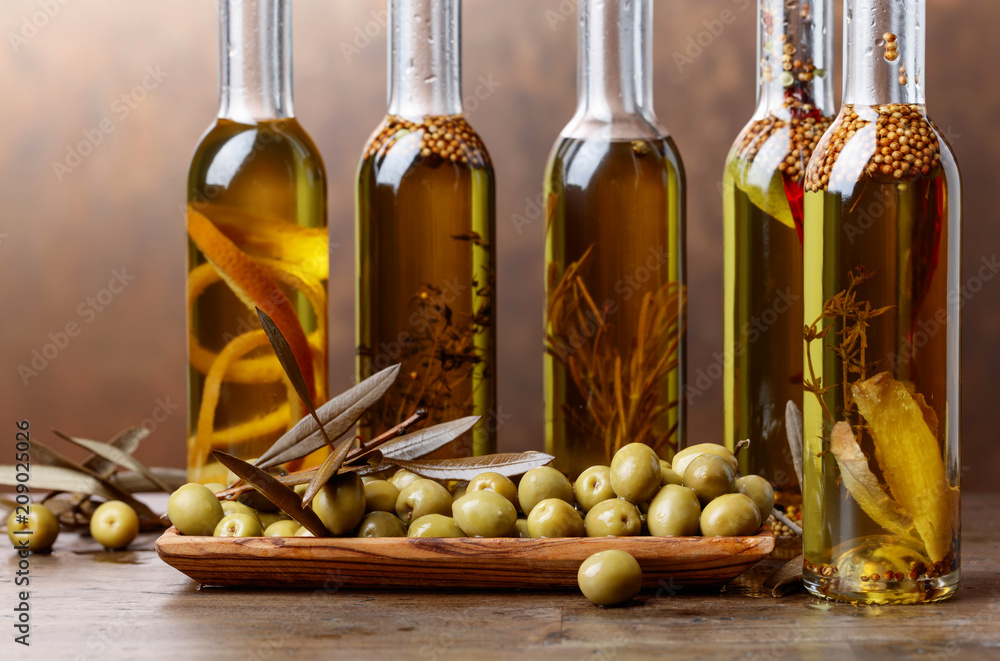 Green olives and bottles of olive oil with warious spices and herbs . Green olives and bottles of olive oil with warious spices and herbs .