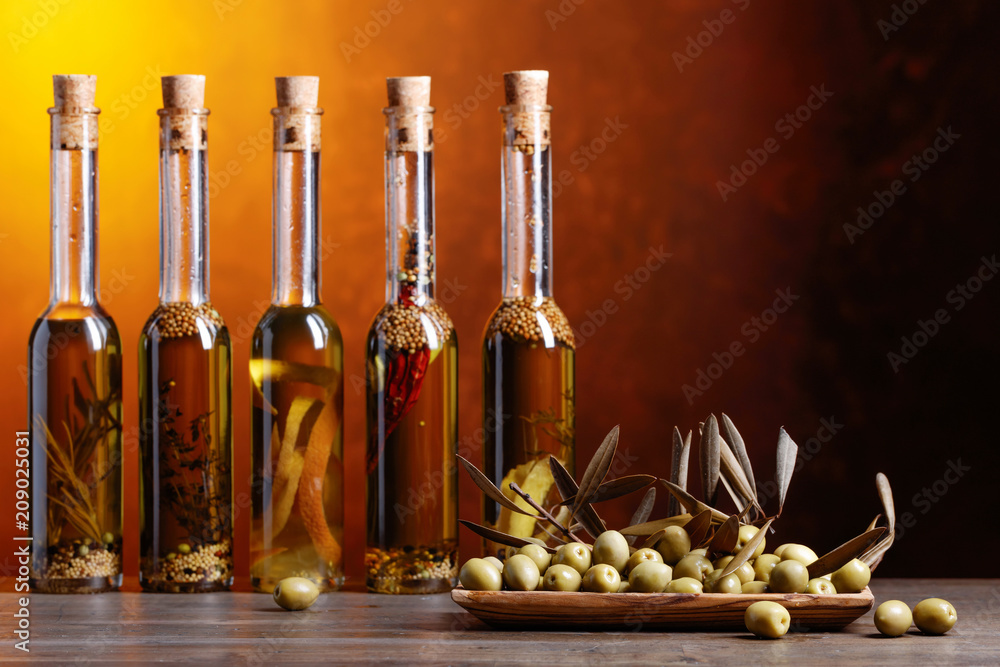 Green olives and bottles of olive oil with warious spices and herbs . Green olives and bottles of olive oil with warious spices and herbs .