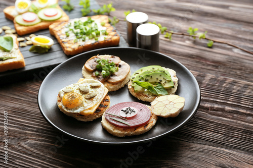 Plate with different delicious toasts on table