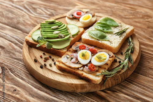 Different delicious toasts on wooden board