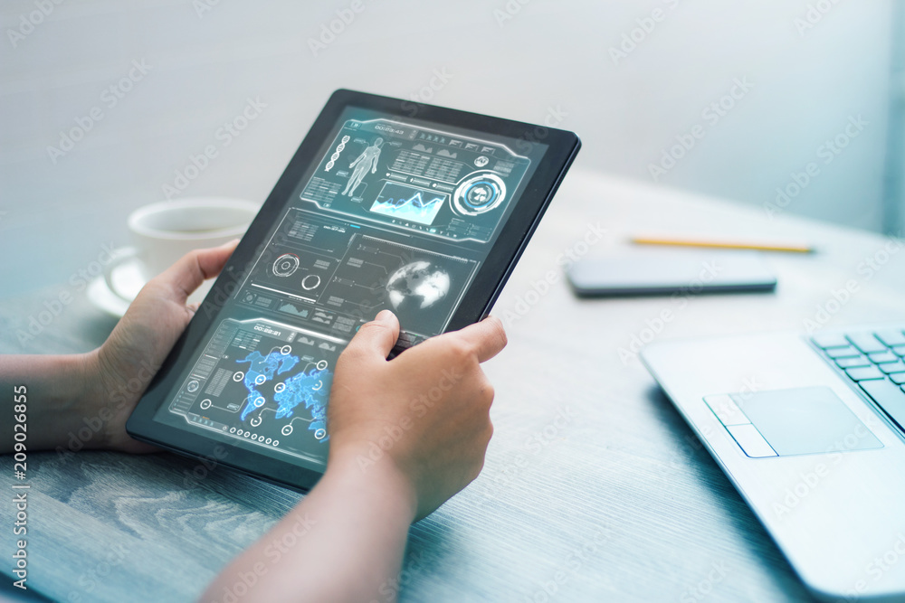Hands of woman using tablet on wooden table with HUD user interface for cyber futuristic technology concept Hands of woman using tablet on wooden table with HUD user interface for cyber futuristic technology concept