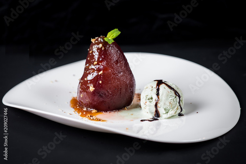 A dessert with caramelized pear and ice on black background