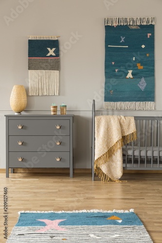 Obraz na płótnie Decor on the wall above grey cabinet and child's bed with blanket in bedroom interior