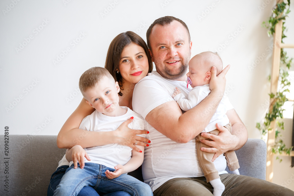 Portrait of happy young parents with two sons sitting on sofa