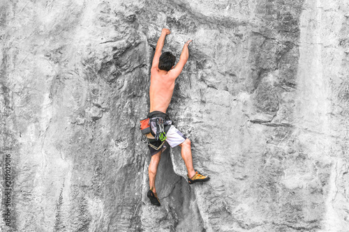 Male rock climber climbing the cliff without a tether