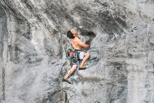 Young male climber climbs on a rock without a safety rope