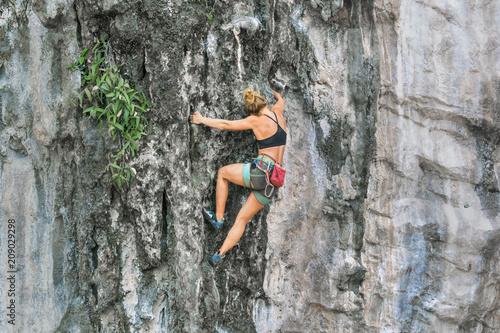 Young female rock climber climbing the cliff without safety equipment