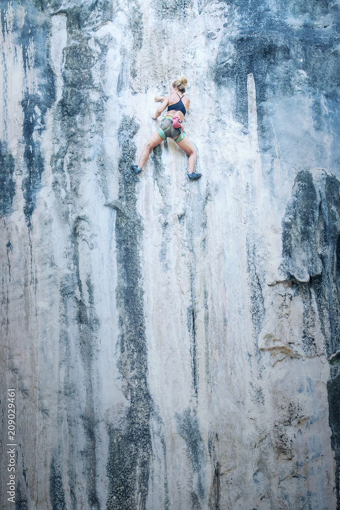 Fototapeta premium Young woman climbing a cliff without insurance. Toned
