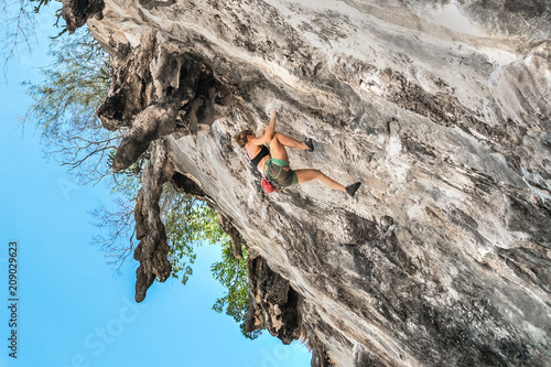 Photos Young woman climbs on a overhanging cliff without safety equipment on a summer d