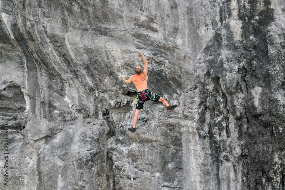 Young man climbs on a rocky wall without insurance Young man climbs on a rocky wall without insurance