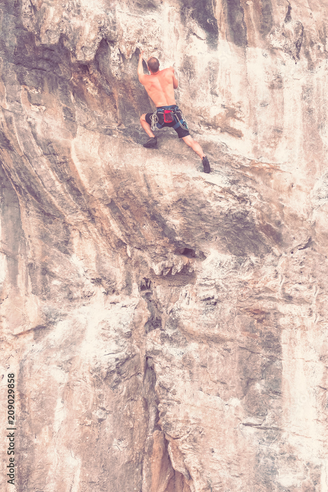 Rock climber on the cliff without insurance equipment. Toned