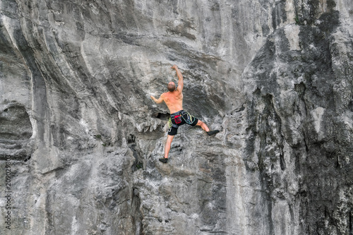 Young man climbs on a rocky wall without insurance