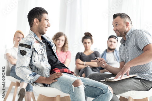 Smiling spanish man talking with counselor during therapy for young people © Photographee.eu