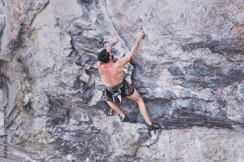 Young bearded man climbing a rock wall without safety rope