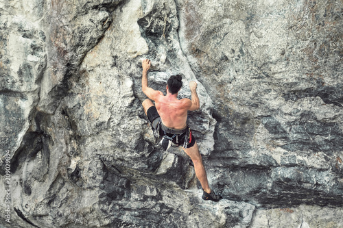 Young male climber climbing a rock wall without safety rope